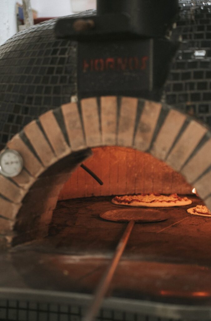 Pizzas cocinándose dentro del horno de leña de Delantal Negro, en la Plaza de los Maldonados de Sevilla