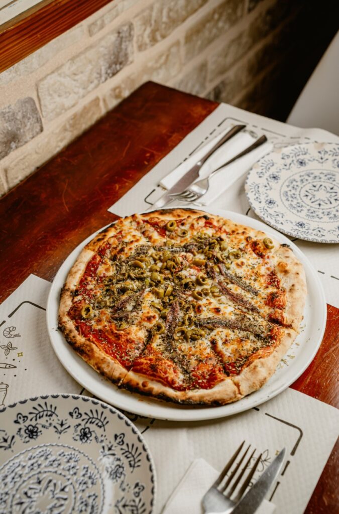 Pizza de anchoas y aceitunas en una mesa de Delantal Negro, Sevilla